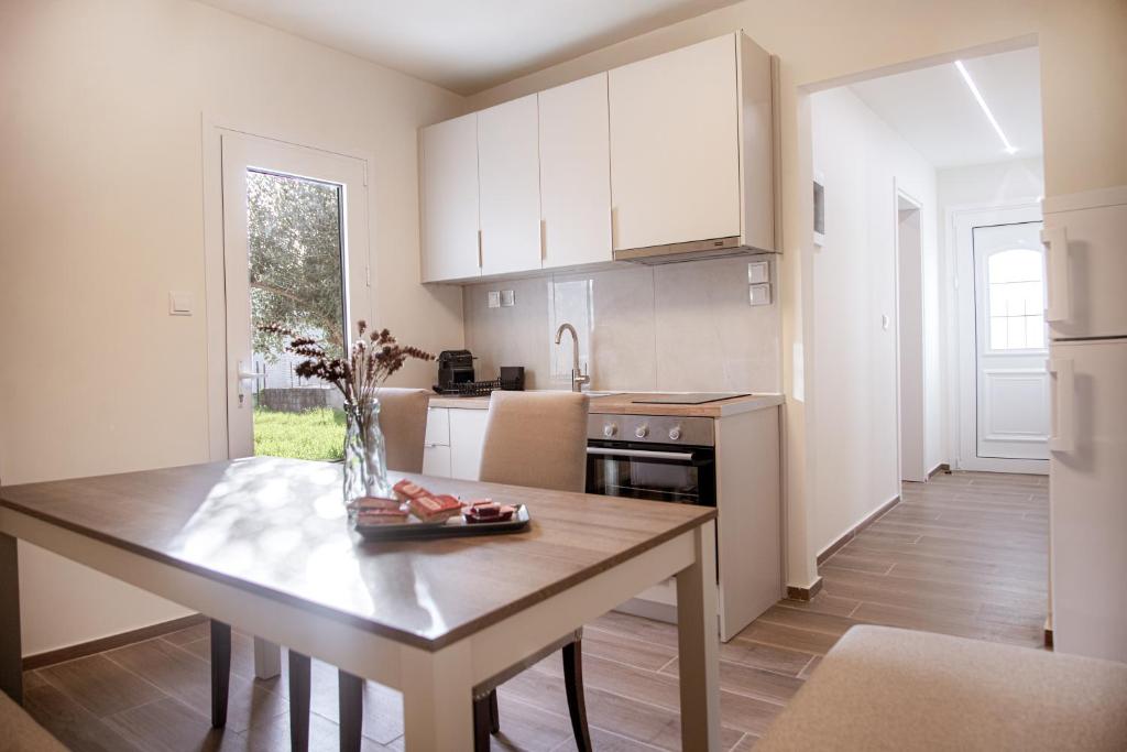 a kitchen with a wooden table and a kitchen with white cabinets at Tailor Garden House in Tríkala
