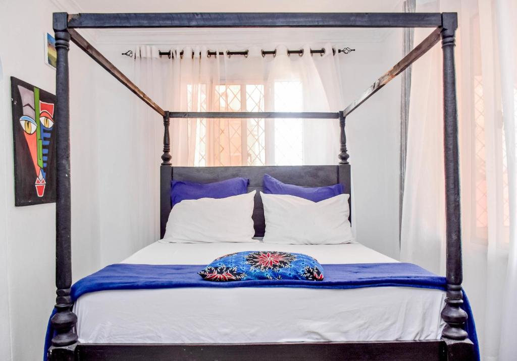 a bedroom with a four poster bed with blue and white pillows at Kilifi Tulivu in Kilifi