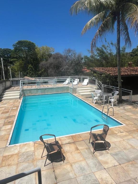 a large swimming pool with two chairs and a palm tree at Casa Country Niterói in Niterói