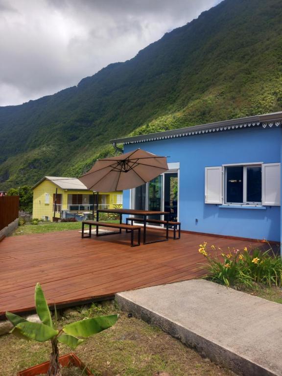 a blue house with a wooden deck with an umbrella at Ti kaz Salazie 1 in Salazie