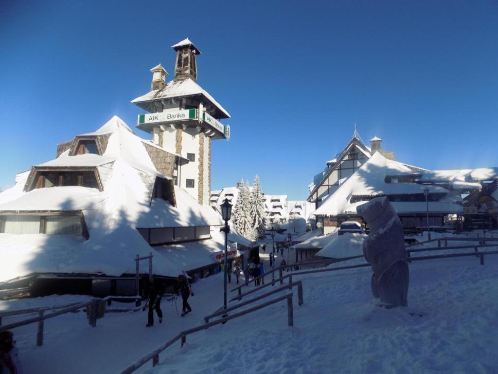 a group of snow covered buildings with a clock tower at Apartment Ski Star Konaci in Kopaonik