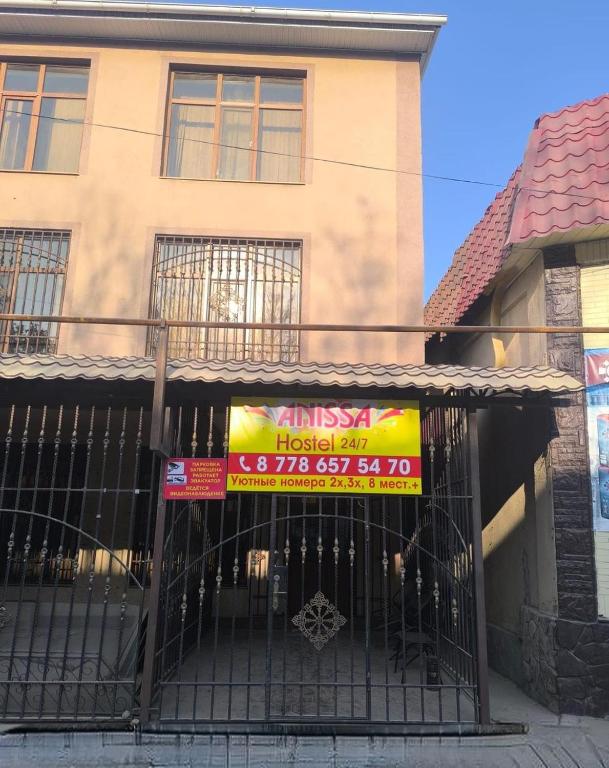 a building with a sign in front of a gate at Anissa in Shymkent