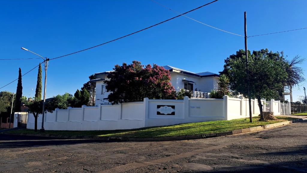 a white fence in front of a house at Oppihoek Gastehuis in Kroonstad