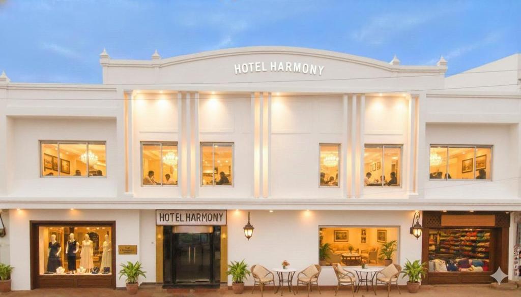a white building with tables and chairs in front of it at Hotel Harmony in Khajurāho