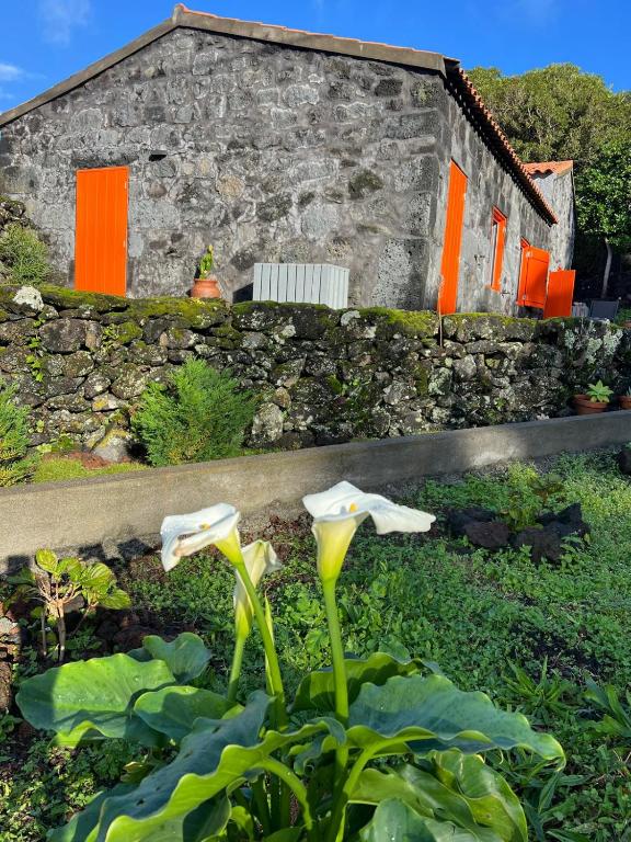 a stone building with orange doors and flowers in front of it at Casa Picobello in Calheta de Nesquim
