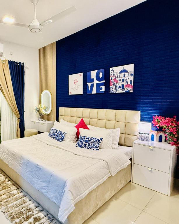 a bedroom with a large bed with a blue wall at Rizz Santorini Apartment in Negombo
