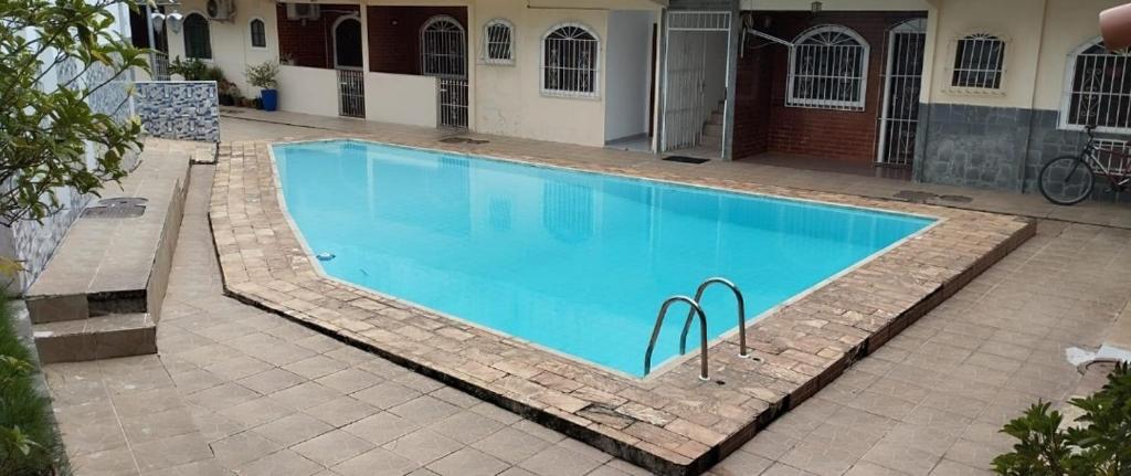 a large blue swimming pool in a courtyard at Suíte da Lagoa in Araruama