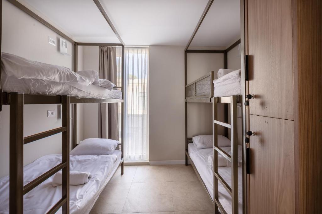 a room with three bunk beds and a window at Jeroom Hostel in Jerusalem