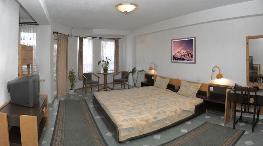 a bedroom with a bed and a table and a tv at Hotel Balevurov in Sandanski