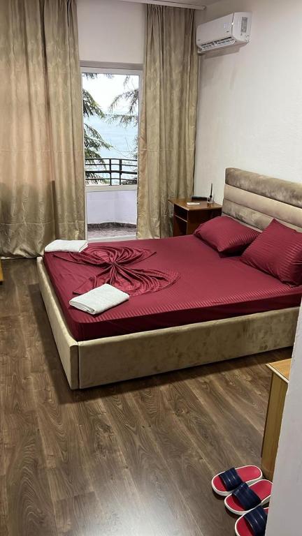 a bedroom with a large bed with red sheets and red pillows at Hotel Te Bakja in Tushemisht
