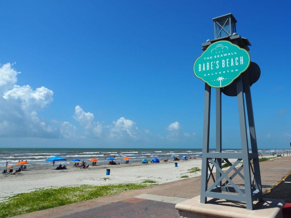 a sign at the beach with people on the beach at Boltons Bungalow Casa Del Mar in Galveston