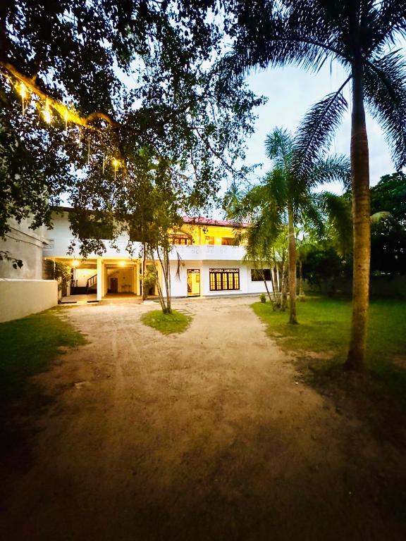 a large white building with palm trees in front of it at Asiri guest house in Dickwella