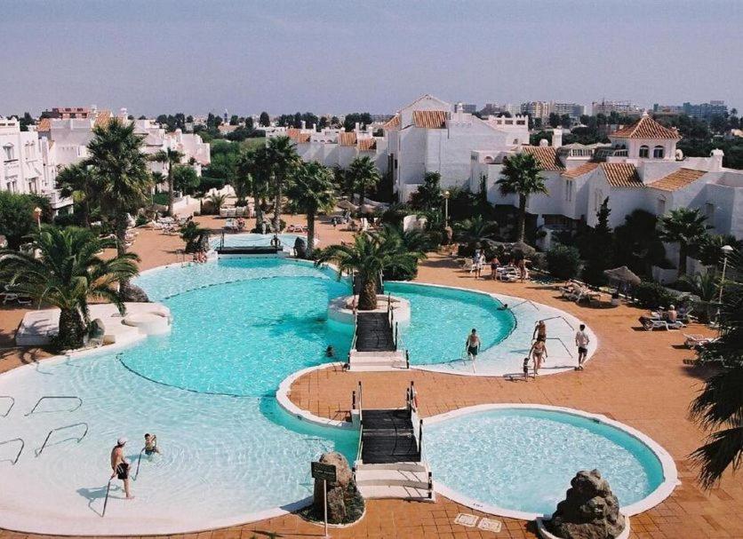 a large swimming pool in a resort with people in it at Apartamento isabel golf center in Almería