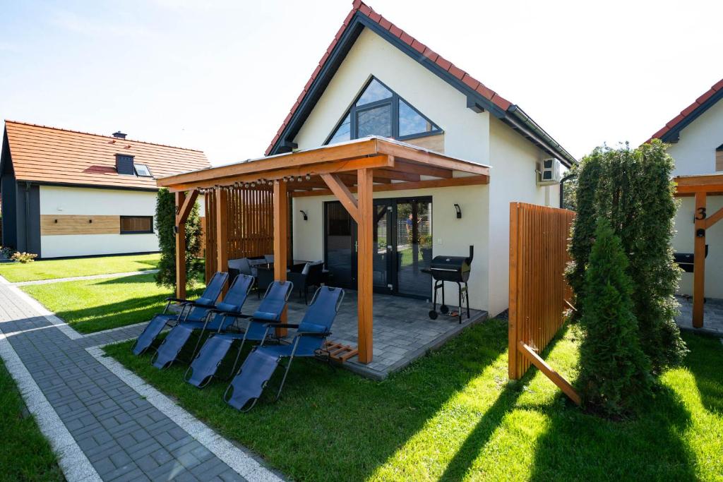 a patio with chairs on the grass in front of a house at Domki Górkło in Górkło