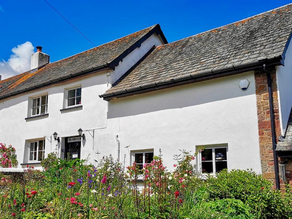 a white house with flowers in front of it at The Millers Cottage in Okehampton