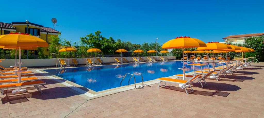 a pool with chairs and umbrellas and a group of tables at Residence Villaggio Alemia in Cropani