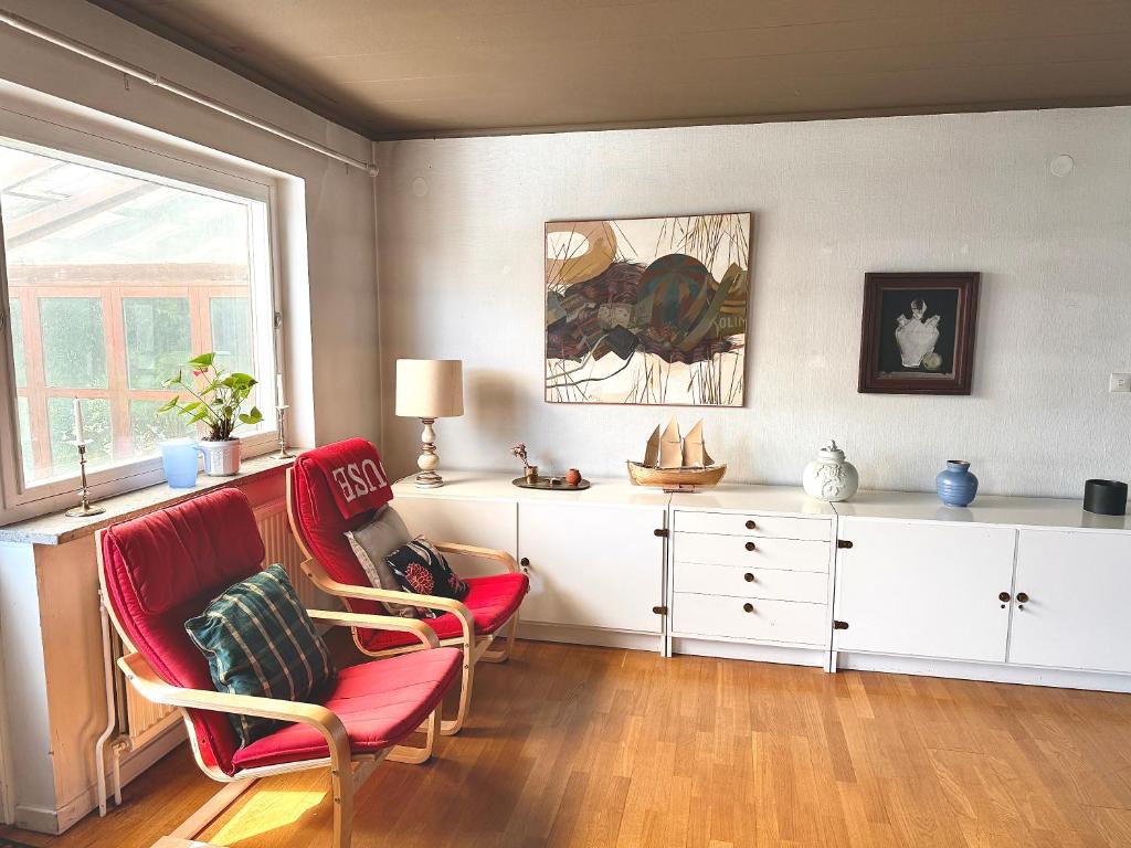 a living room with two red chairs and a dresser at Villa in central Visby in Visby