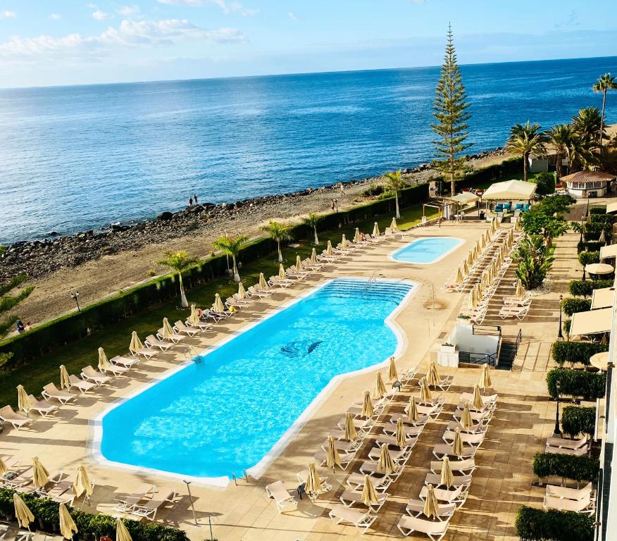 an overhead view of a pool with chairs and the ocean at Canopael in Mogán