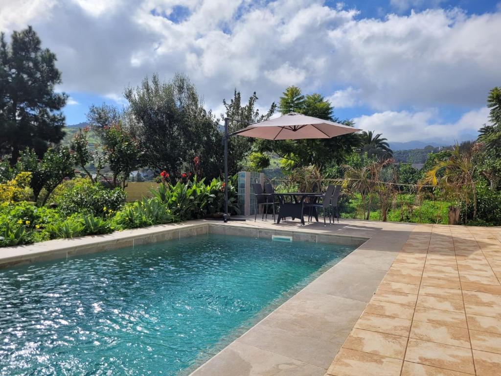 a swimming pool with an umbrella next to a table and a table at House with a heated pool for your exclusive use in Santa Brígida