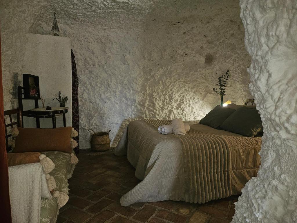 a bedroom with a bed in a stone wall at Cueva El Madrono in Pegalajar