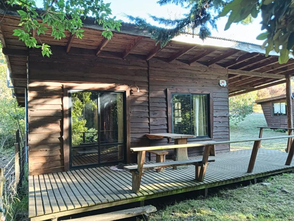 a cabin with a picnic table on a deck at Cabañas Río Iculpe in Lago Ranco