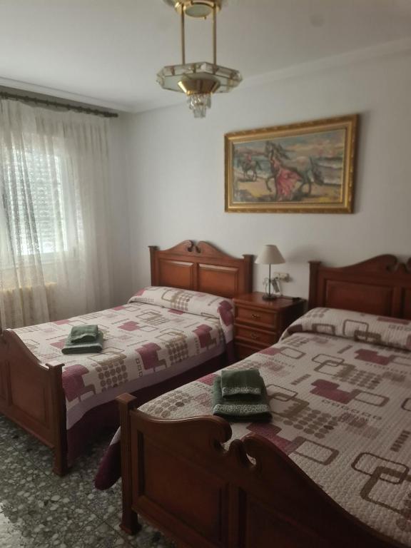 a bedroom with two beds and a chandelier at Dos Hermanas in Sahagún