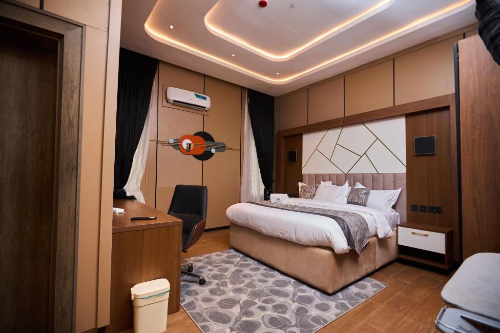 a bedroom with a large bed and a desk with a lamp at Bourdillon Hotel and apartments in Gwarinpa