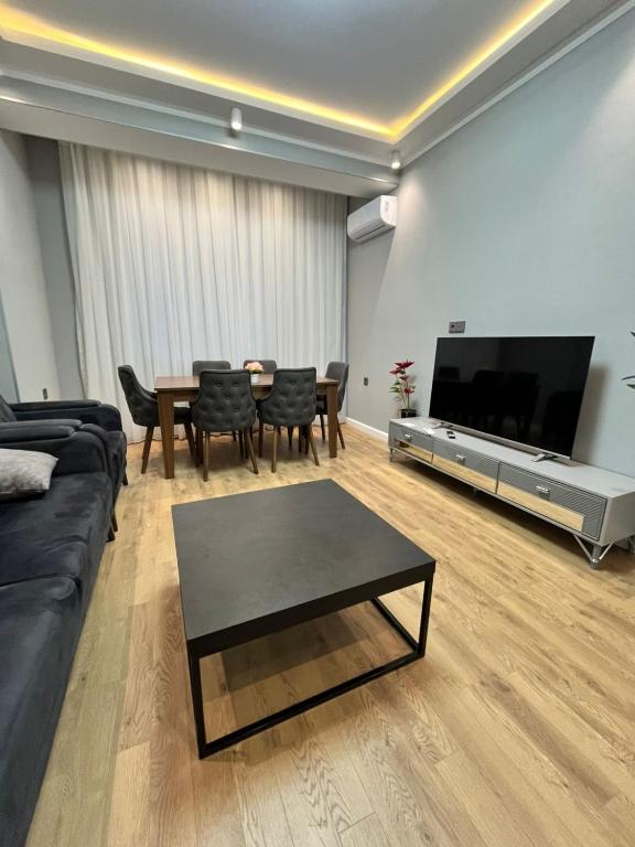 a living room with a couch and a table and a tv at Qarb Apartment Dernegul metro in Baku