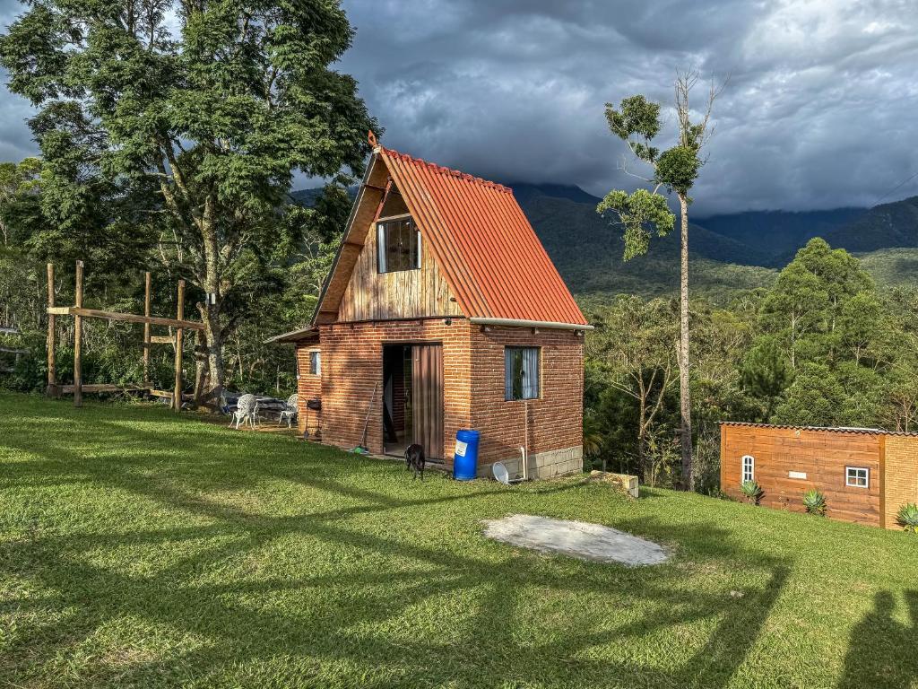 a small house with an orange roof on a field at Chalé Agulhas Negras in Resende