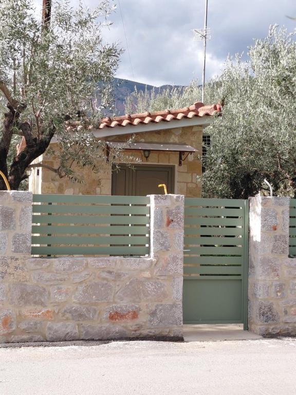 a house with a green gate and a stone wall at Sweet little studio in Leonidio