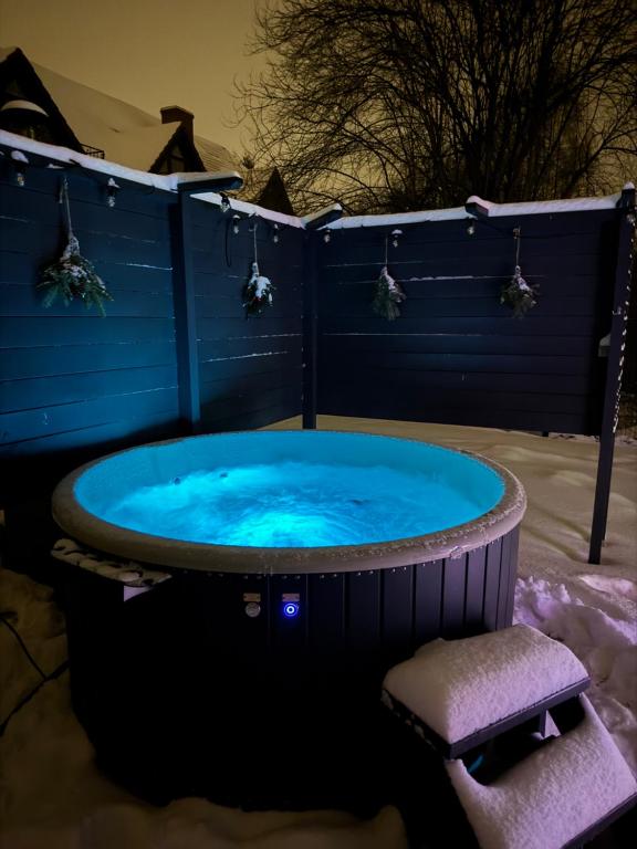 a hot tub in the snow with a chair in it at Dom na Zadzielu - domek z balią nad Jeziorem Żywieckim in Żywiec