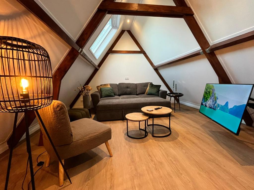 a living room with a couch and a tv in a attic at B&B Mirre in Kapelle
