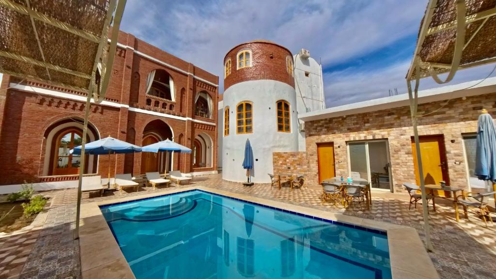 a swimming pool in front of a building with a tower at Golden Land in ‘Ezbet Abu Ḥabashi