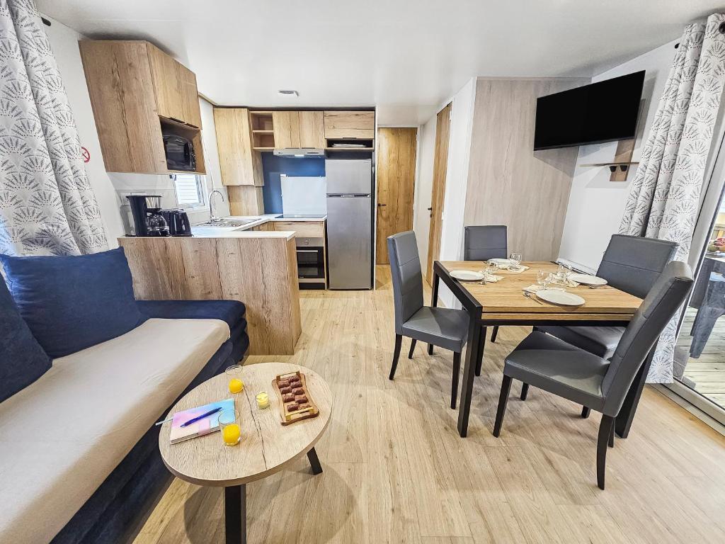 a living room with a couch and a table with chairs at Séjour en Forêt 4 étoiles in Litteau