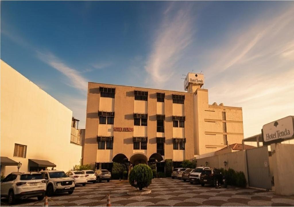 a building with cars parked in a parking lot at Hotel Tenda in Marília