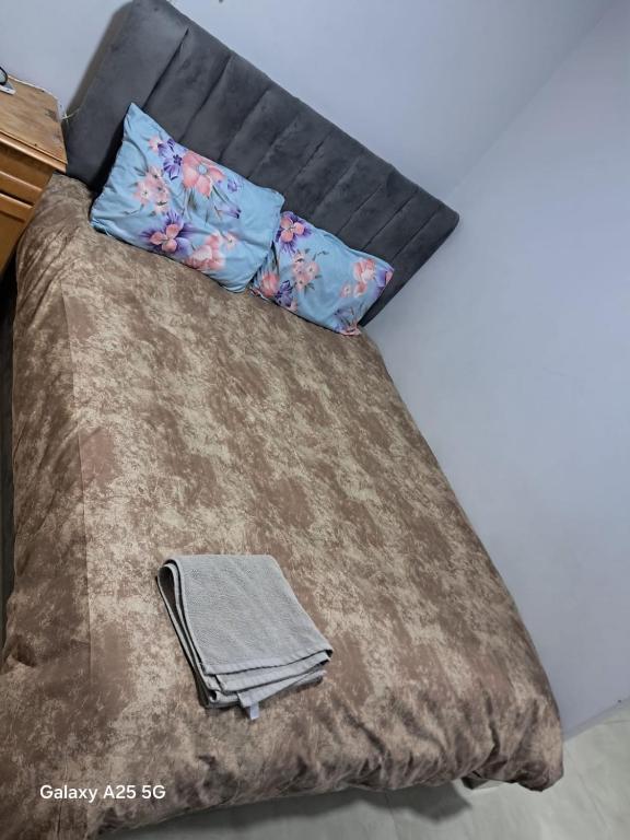a bed with a brown comforter and two pillows at Cozy Private Studio DBL in ‘Ezbet `Abd el-Ḥamîd