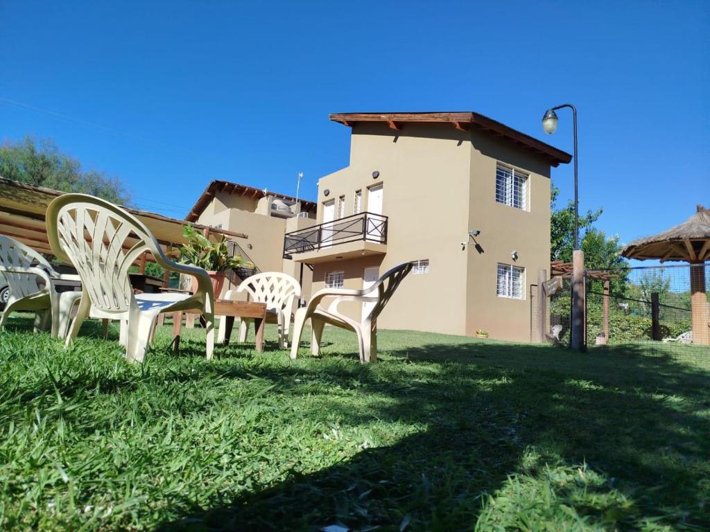 a group of chairs sitting in the grass in front of a house at La Serena Cabañas in Potrero de los Funes