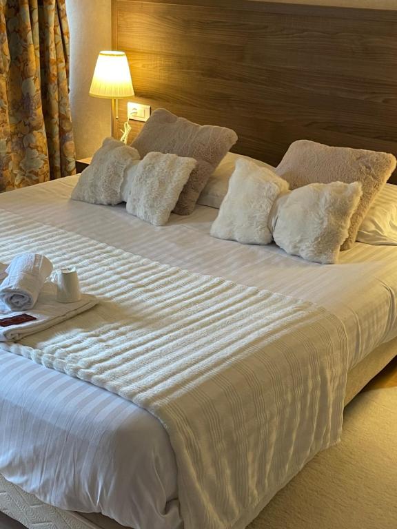 a large white bed with pillows and a tray on it at Hôtel du Commerce in Semur-en-Auxois
