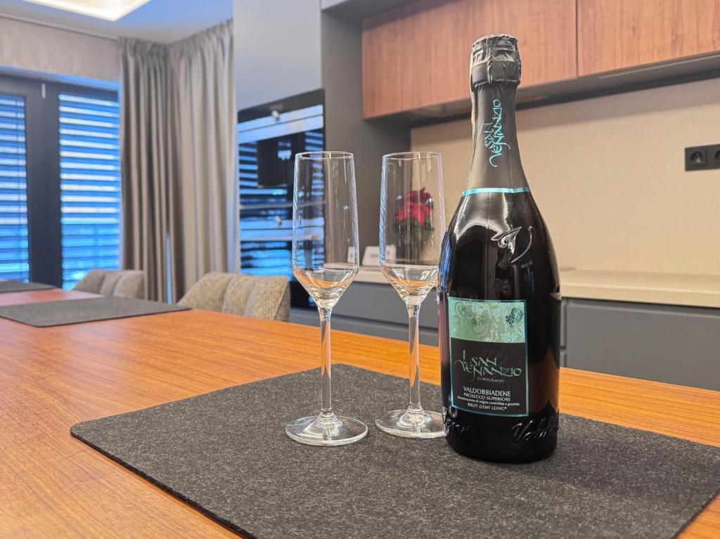 a bottle of wine sitting on a table with two wine glasses at LUXURY SUITE Boží Dar in Boží Dar