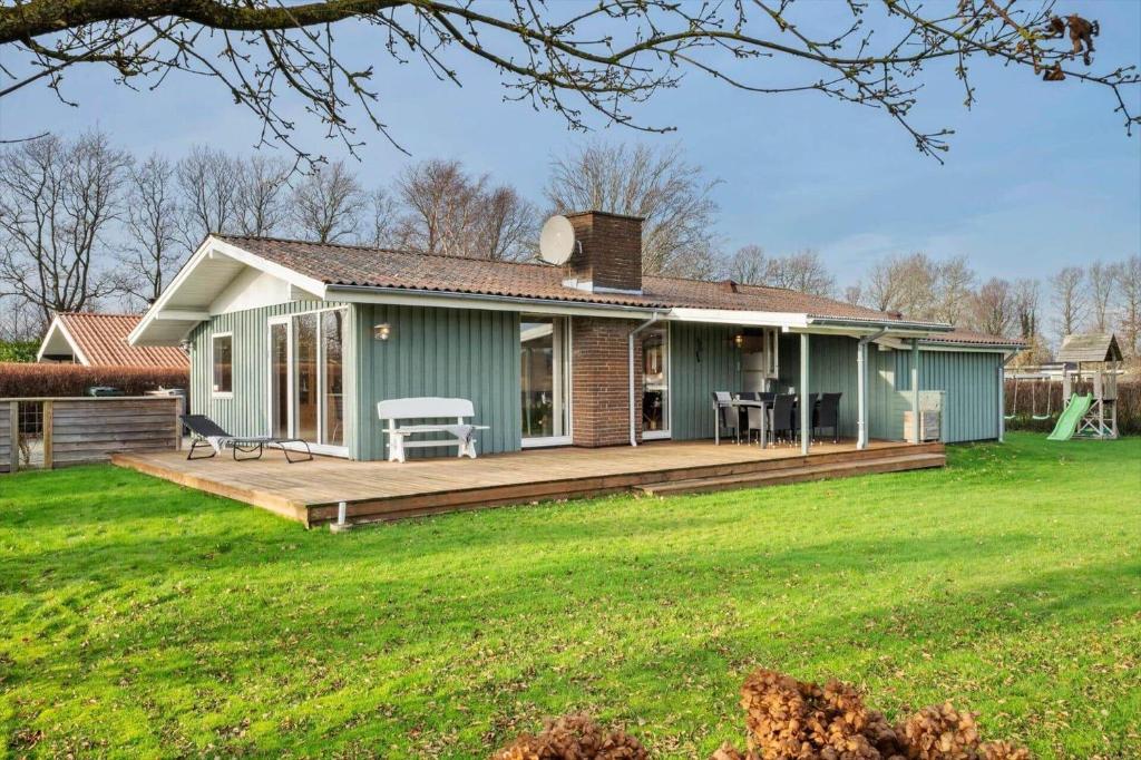 a green house with a large wooden deck at SJ316-Hejls-Ronnebaervaenget-9 in Hejlsminde