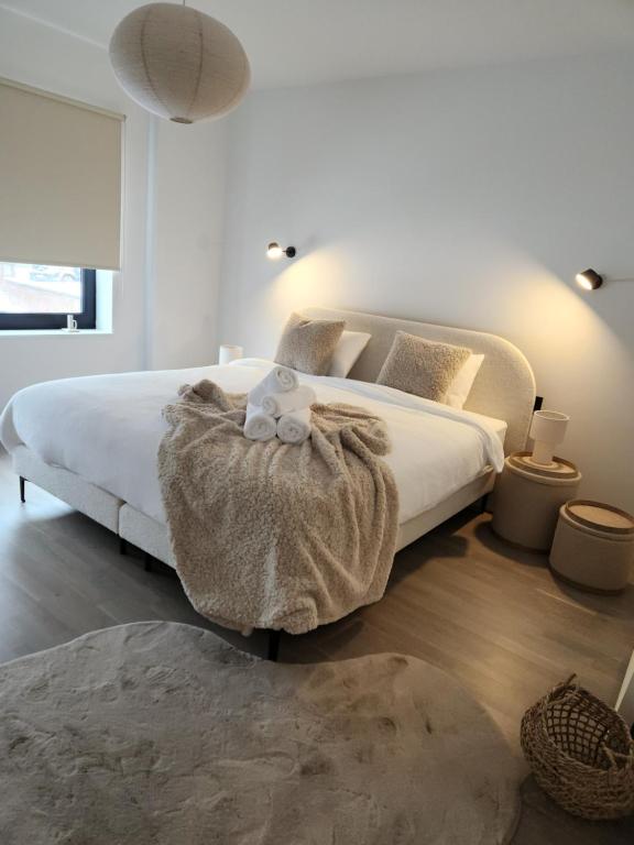 a white bedroom with a bed with a teddy bear on a table at Verliefd in Brustem in Sint-Truiden