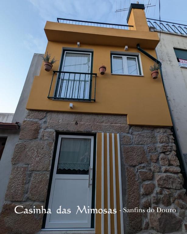 a building with a door and a balcony at Casinha das Mimosas in Sanfins do Douro