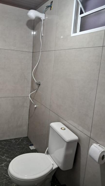 a bathroom with a white toilet and a window at APARTAMENTOS02 TERREO 01 quarto in Jaguaruna