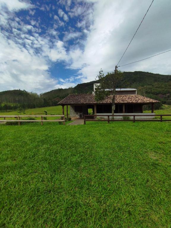 a house in the middle of a field with a green field at Hostel e Camping Vale Mirante da Rocha in Timbe do Sul