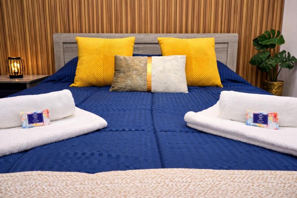 a large bed with blue sheets and yellow pillows at Marble Coast Studio Apartment in Larnaca