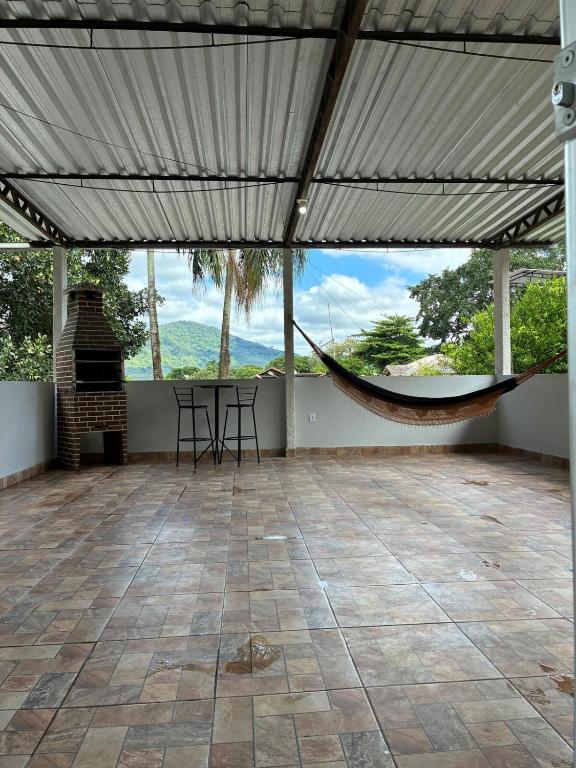 a hammock in a room with a table and a fireplace at Refúgio Rio Soberbo in Guapimirim