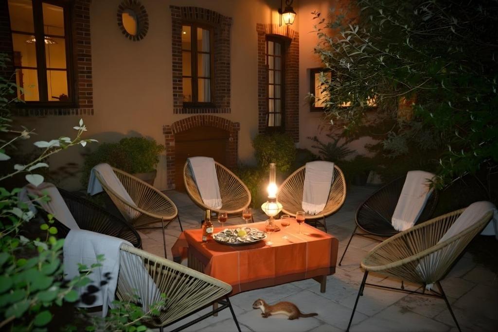 a patio with chairs and a table with a candle at Séminaire Comme à la Maison - cosy, écossais & productif en Sologne in Aubigny-sur-Nère