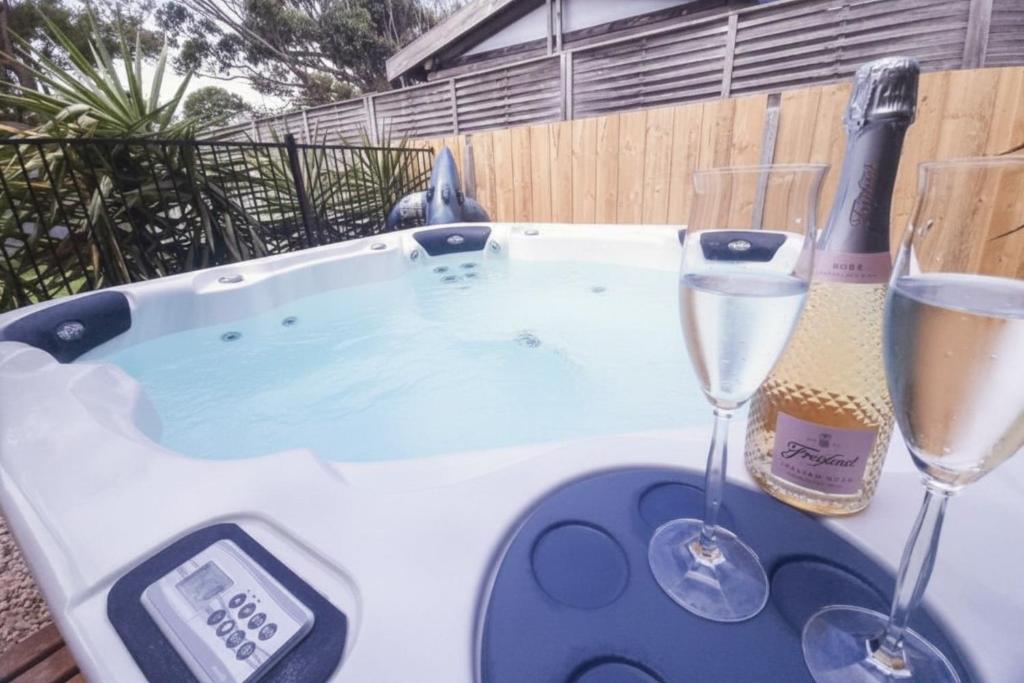a hot tub with two glasses of wine and a thermometer at Spacial Rend in Cape Woolamai