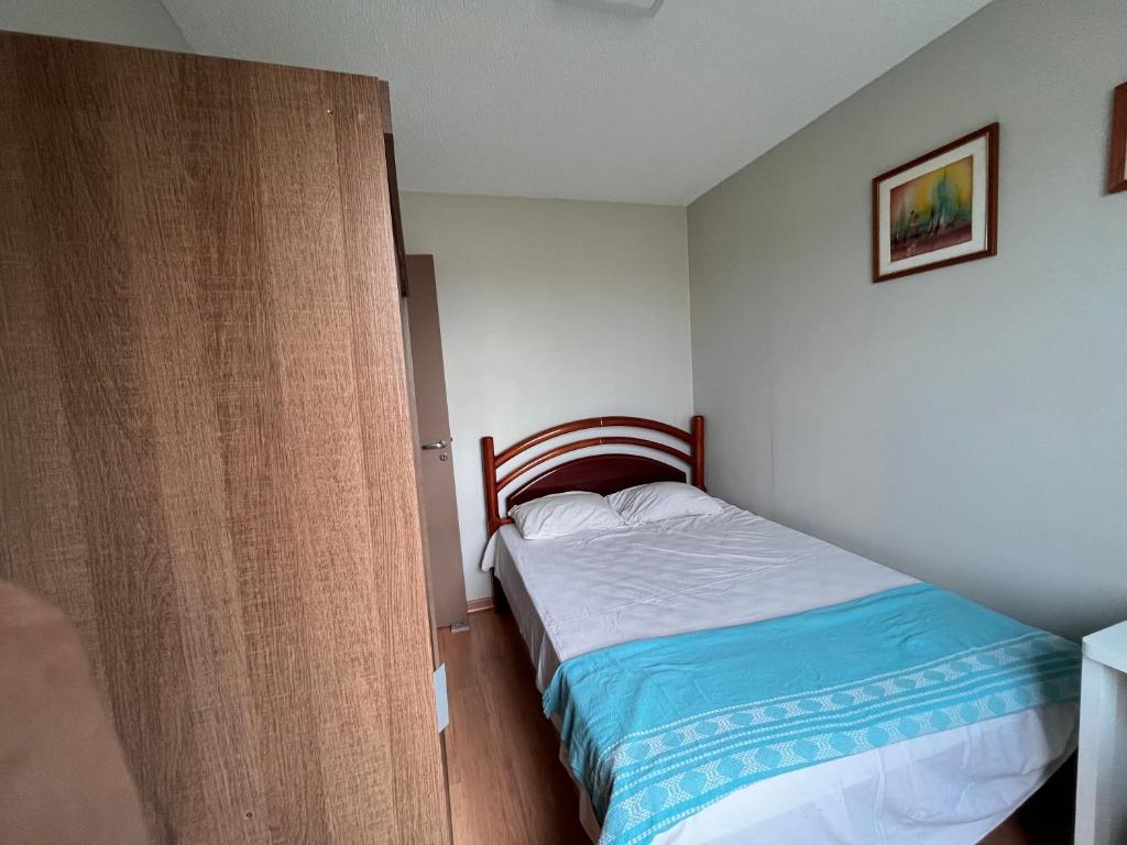 a small bedroom with a bed and a wooden door at Quarto Premium c Ar e Wi-Fi - Próximo à Ponte JK in Brasília