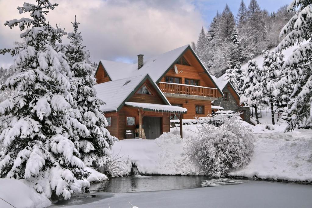 a log cabin in the snow next to a river at Chata nad stawem in Wierchomla Mała